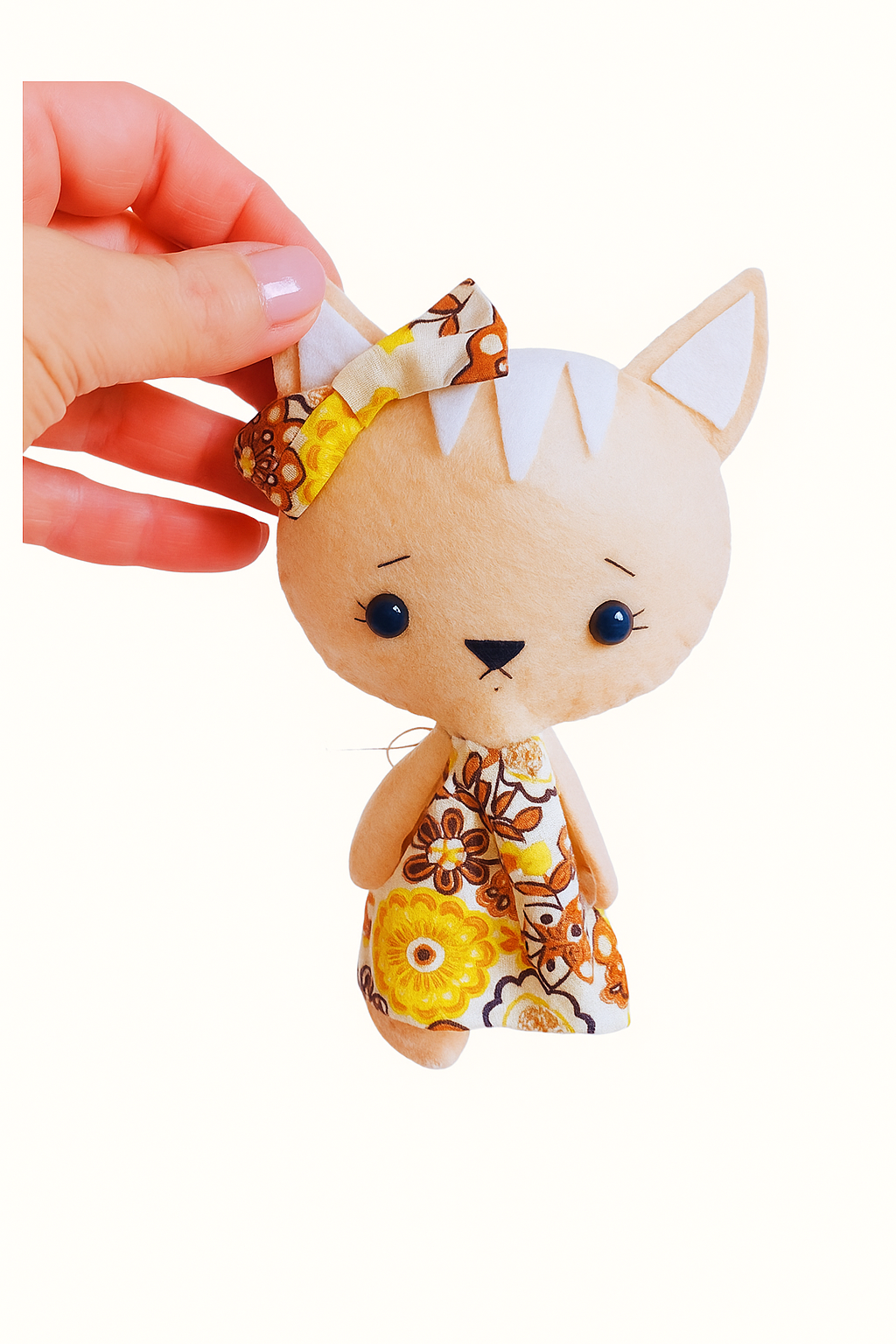 Small plush toy cat held by a hand with a white background