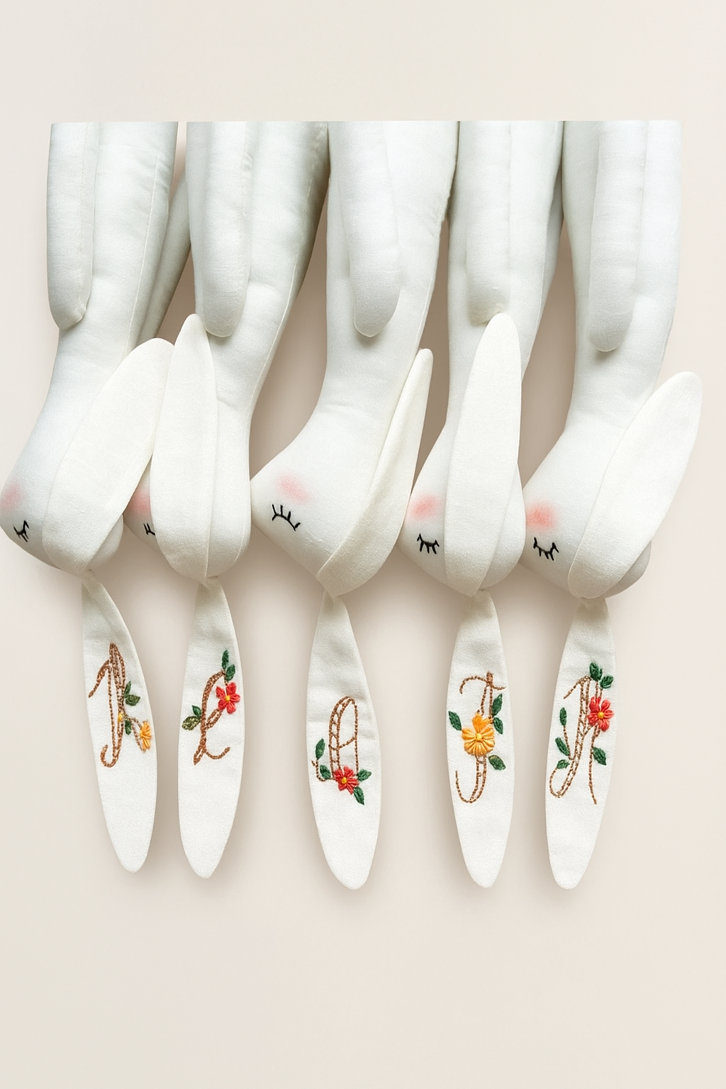 Handmade white plush bunnies with long ears featuring delicate colorful floral embroidery, designer stuffed toy for nursery decor