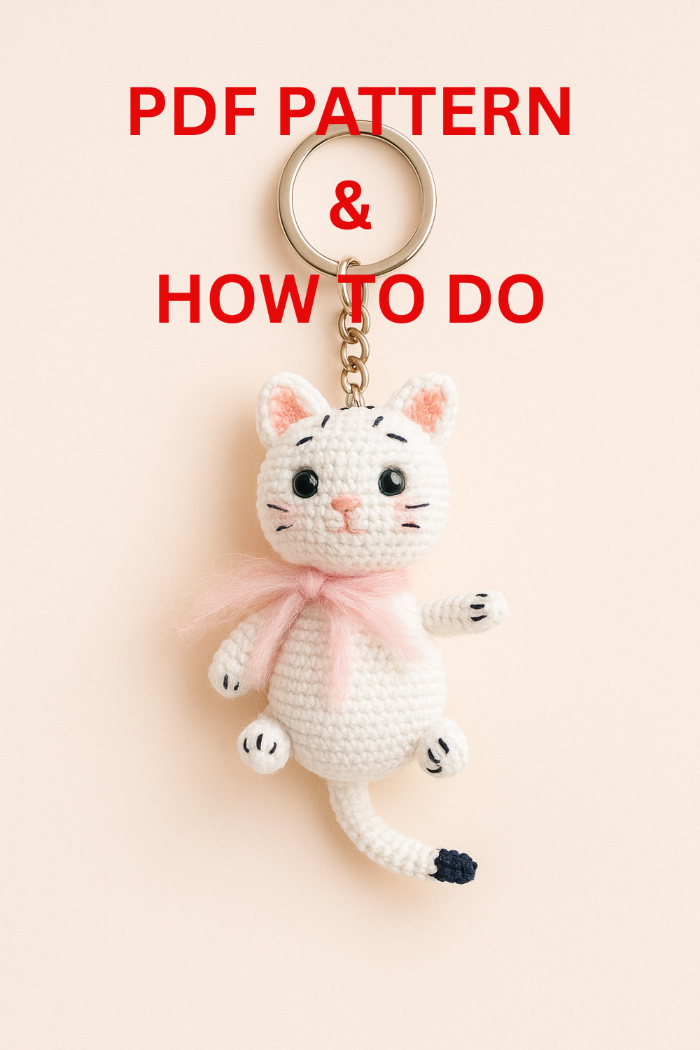 A small white crochet cat keychain with a pink scarf, handmade in amigurumi style